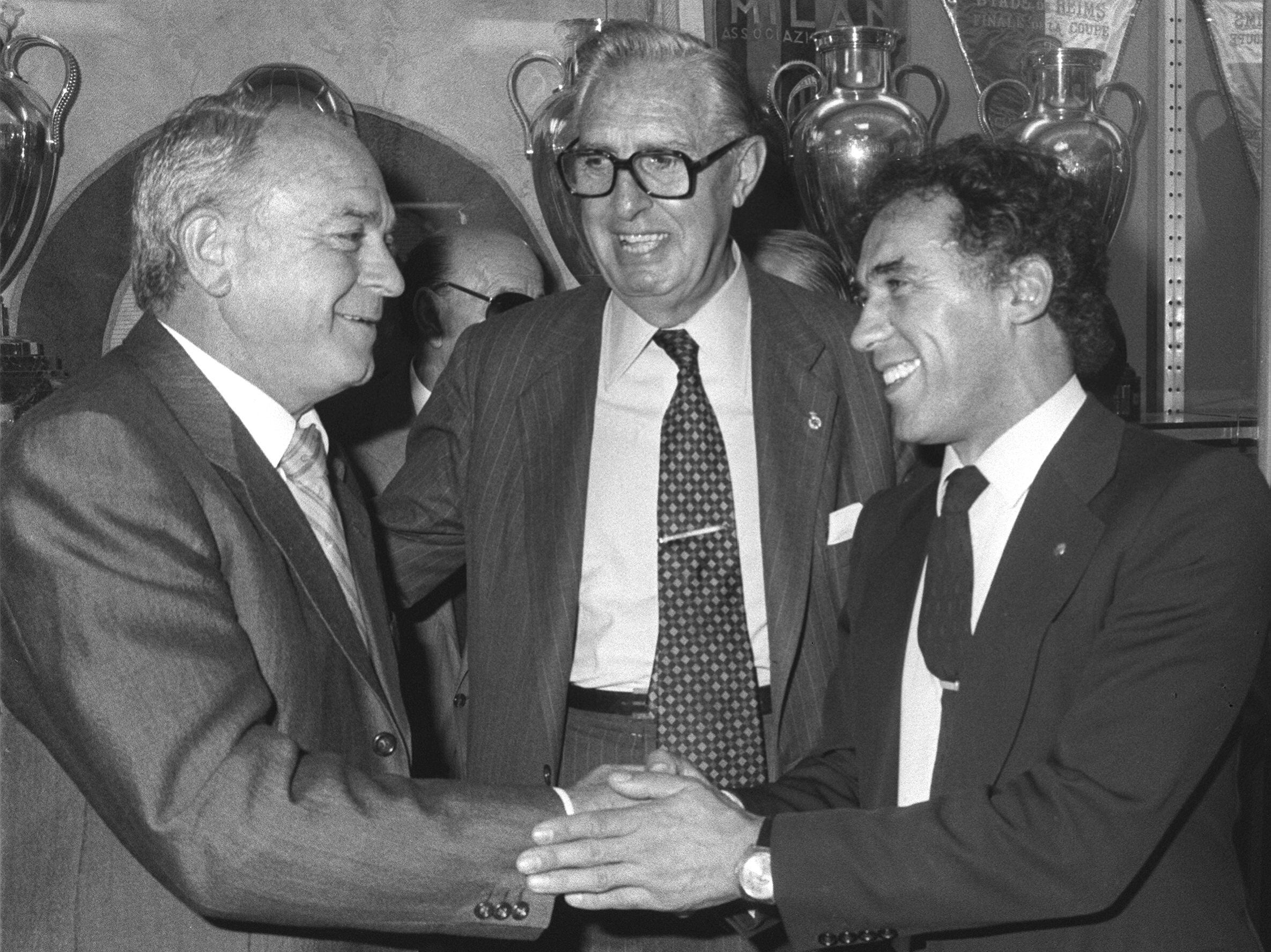 Alfredo di Stéfano (a la izquierda) y Amancio Amaro (a la derecha), se saludan en presencia del presidente del Real Madrid, Luis de Carlos, tras formalizar el compromiso oficial de ambos como entrenadores del Real Madrid y del Castilla, respectivamente, en 1982.