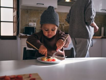 Un niño come fruta en la cocina.