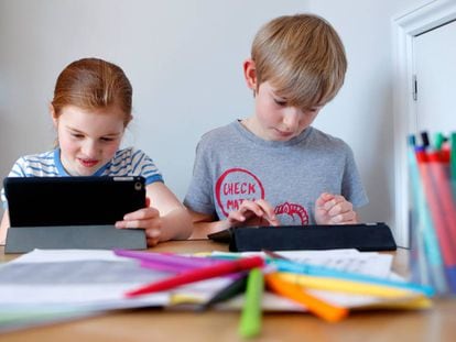 Dos niños realizan tareas escolares a través de sus tabletas electrónicas. 