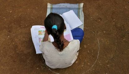 Una niña, que se ha perdido sus clases en Internet debido a la falta de conexión, se sienta en el suelo dentro de un círculo para mantener una distancia segura mientras escucha lecciones pregrabadas, en Dandwal, Maharashtra (India).