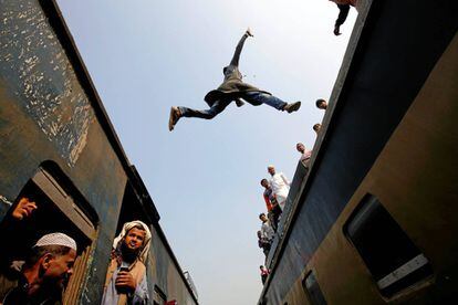 Un viajero salta de un tren a otro al llegar a una estación, a las afueras de Daca (Bangladés), el 17 de enero.