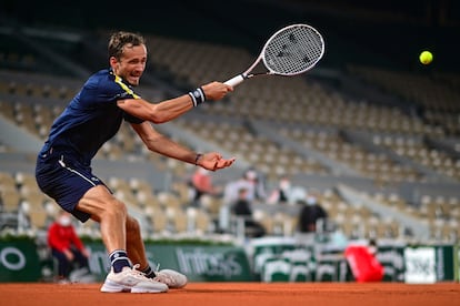 Medvedev hits the ball, with the center stands empty.