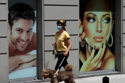 Una chica con su perro pasea con mascarilla por una céntrica calle de Gijón.