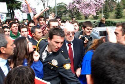 El rector de la Universidad Complutense, Carlos Berzosa, escoltado por los guardias para protegerle de la multitud.