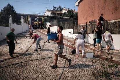 Vecinos de Caneças montan una cadena humana con cubos de agua para intentar apagar las llamas que amenaza sus viviendas.