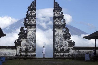 Un hombre observa el volcán Agung, cubierto de nubes, desde un templo de Karangasem (Indonesia).
