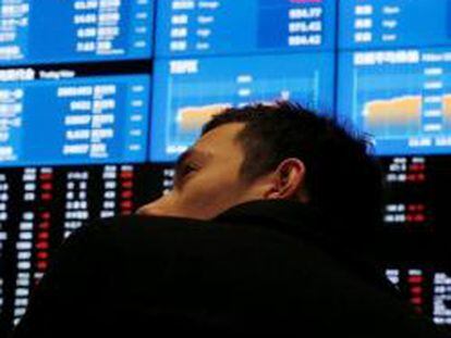 Imagen de un hombre mirando un panel de cotizaciones en la Bolsa de Tokio.