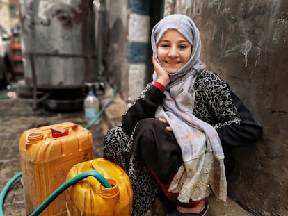 A Yemeni girl gets water in jerry cans at a supply point.