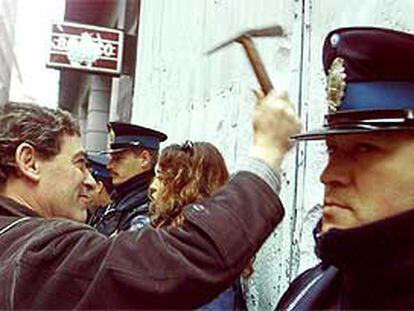 Un manifestante da martillazos en la fachada de un banco de Buenos Aires.