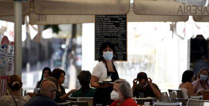 Una camarera con mascarilla atiende a los clientes en una terraza de un bar en Madrid.