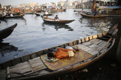 Una barca en el río Buriganga sirve de lugar de descanso a un joven en Daca, Bangladesh. 18 de mayo de 2014.