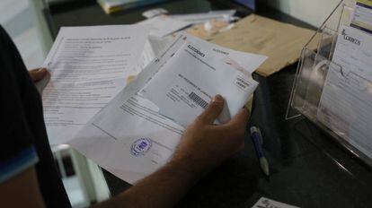 Un ciudadano presenta en una oficina de Correos la documentación con sus papeletas para votar por correo en las elecciones del 26- J.