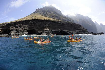 Varios excursionistas en kayak frente al acantilado de Los Gigantes, en Tenerife (Islas Canarias).