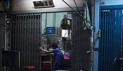 Una mujer entra en su casa de Bangkok. En la televisi&oacute;n se emite una telenovela.