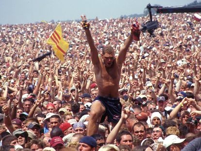 Un hombre se alza sobre la multitud que atestó el festival Woodstock, en Rome (Nueva York) en julio de 1999.