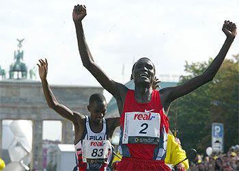Paul Tergat atraviesa la meta del maratón de Berlín seguido por Sammy Korir y con la Puerta de Brandenburgo al fondo.