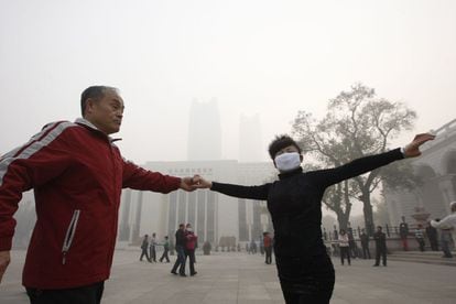 Una pareja ensaya un baile en una de las plazas de la ciudad de Harbin (China), 21 de octubre de 2013. Algunos transportes públicos han suspendido el servicio debido a la grave situación.