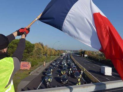 Un manifestante vestido con un chaleco amarillo ondea una bandera francesa en Toulouse, durante la jornada de movilizaci&oacute;n contra la subida de los impuestos de la gasolina