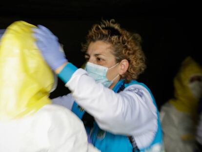 Sanitarios del SUMMA se visten con material protector frente al Covid-19 antes de entrar en el hospital temporal de IFEMA para trasladar a un paciente de la UVI de IFEMA al Hospital Puerta de Hierro.