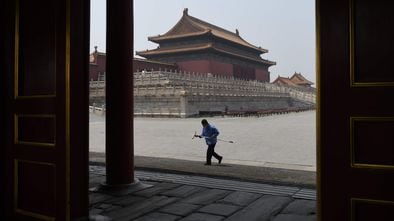 Un empleado de limpieza con mascarilla camina por la Ciudad Prohibida, este viernes 1 de mayo