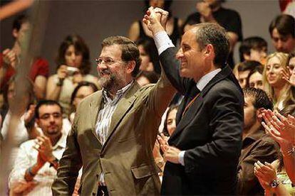 Mariano Rajoy y Francisco Camps levantan sus manos entre los aplausos de los militantes del PP.