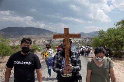 Un joven carga una cruz con el nombre de  Debanhi Escobar.