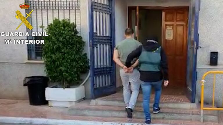 Un agente de la Guardia Civil acompaña a uno de los detenidos en Torrevieja (Alicante).