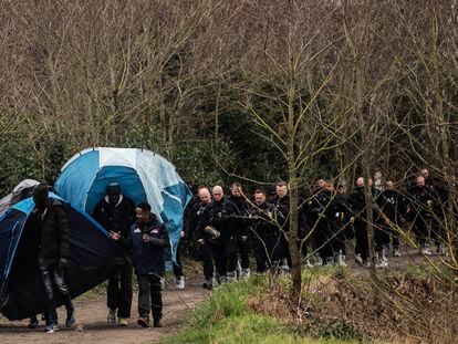 Un grupo de migrantes cargan con las tiendas que les han tirado la policia francesa al desmantelar un pequeño campamento en Calais, Francia