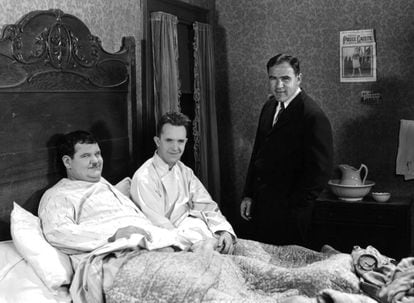 Oliver Hardy y Stan Laurel, ambos en la cama mientras ruedan una escena. De pie, el productor que les estafó, Hal Roach.