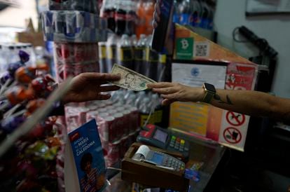 Una persona entrega cambio en moneda estadounidense a un cliente en Caracas, Venezuela.