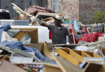 Un hombre lanza una tabla de madera a la montaña de escombros que rodea su casa, en Prairieville, Luisiana (EE.UU).