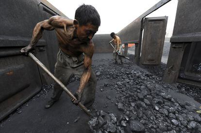 Dos trabajadores descargan carbón en un almacén en la estación de ferrocarril de Hefei, en la provincia china de Anhui.