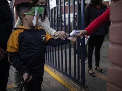 Al estudiante Román Catalán, de seis años, le toman la temperatura antes de ingresar al edificio para su primer día de clases presenciales, este marzo en Chile.