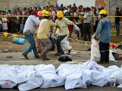 Hombres cargan un cuerpo en el lugar del accidente, cerca de Tuxtla Gutiérrez, en Chiapas.