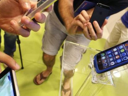 Varias personas prueban tel&eacute;fonos en una tienda de Madrid