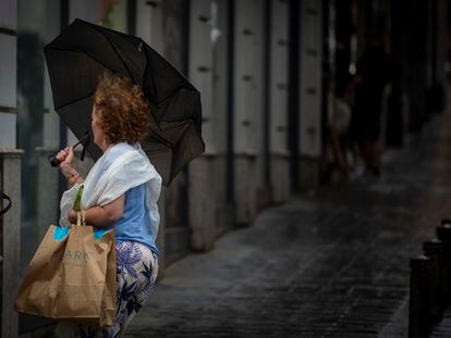 Una mujer sujeta su paraguas este domingo en el distrito de Usera, en el suroeste de Madrid.