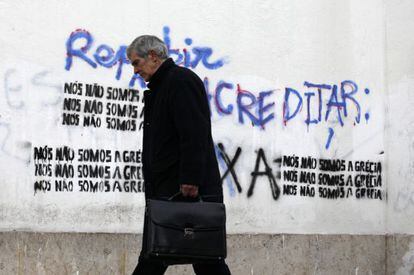 Lisboa, 1 de marzo: un hombre camina junto a una pintada que dice: &quot;No somos Grecia&quot;