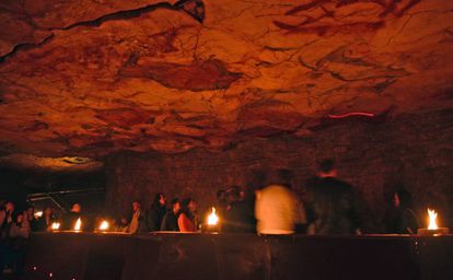 Visitantes en la neocueva de Altamira iluminada con lámaras de tuétano.