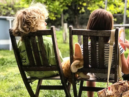 Dos niños conversan en un jardín.