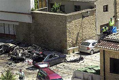 Los cadáveres aparecen en la foto cubiertos por una sábana entre los coches destrozados, mientras agentes de la Guardia Civil inspeccionan la zona.