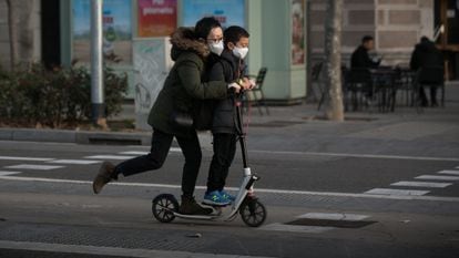 Dos jóvenes en patinete por paseo de Sant Joan, en Barcelona.