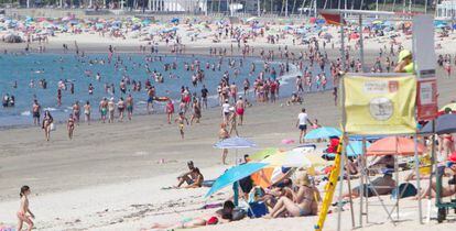 Personas disfrutan del sol y las altas temperaturas este domingo, día de las elecciones gallegas, en la playa de La Fuente en Vigo, Pontevedra.