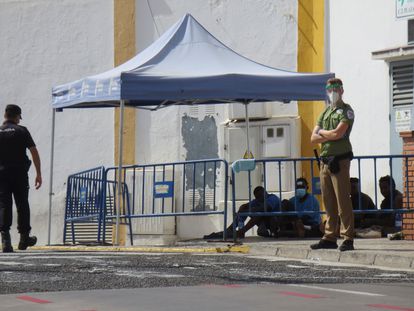 Un policía y un guarda de seguridad vigilan a un grupo de inmigrantes indocumentados que saltaron la valla de Melilla en agosto del año pasado.