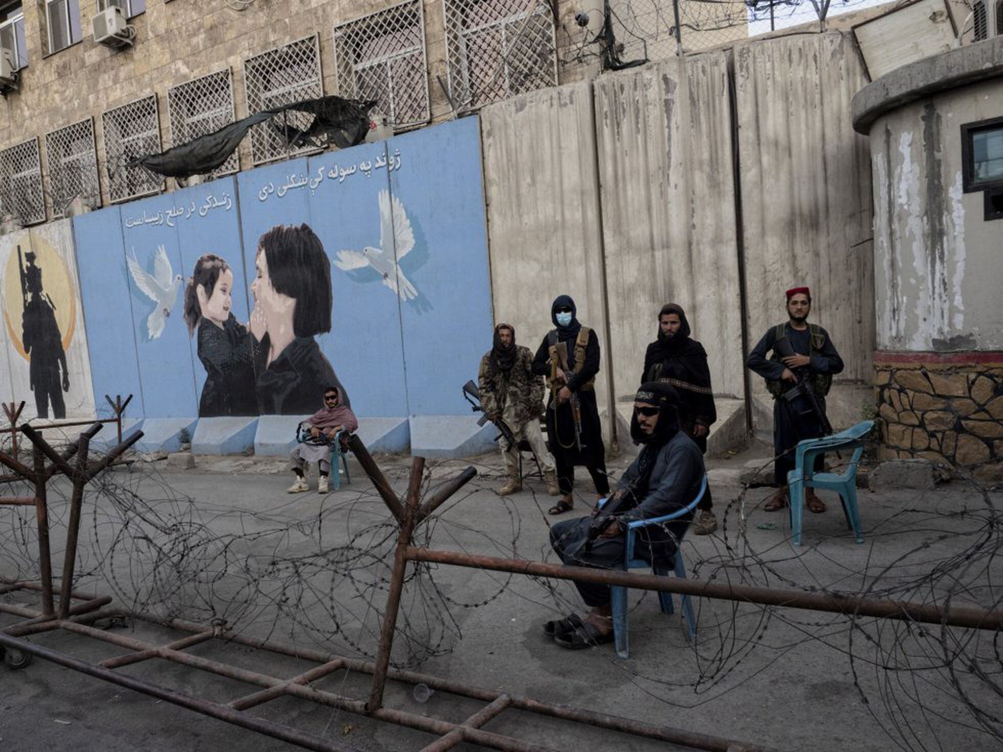 Un grupo de talibanes monta guardia en Kabul ante un cartel que representa a una mujer y a una niña.