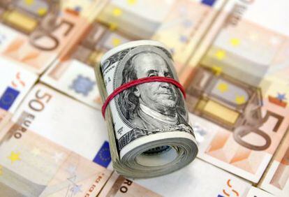 Un rollo de billetes de dólar, junto a otros de 50 euros.