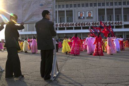 Unos hombres sujetan carteles con propaganda durante la actuación de unas bailarinas en el exterior del Estadio de Pyongyang. Corea del Norte celebra el 101 aniversario del nacimiento de su fundador, Kim Il-sung.
