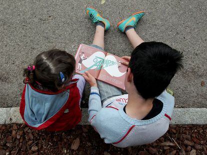 Unos niños leen un cuento infantil en la Feria del Libro de Madrid.