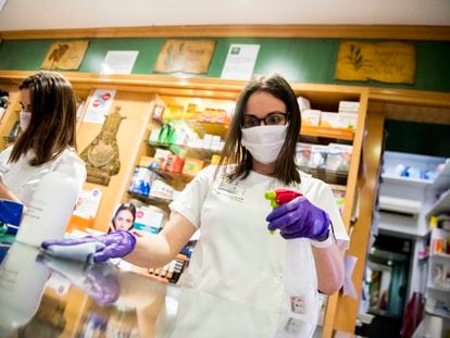 Una farmacéutica desinfecta el mostrador de una farmacia en Granada.