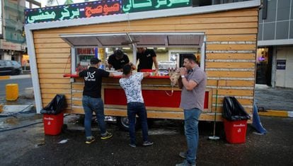 Tres iraqu&iacute;es junto a un restaurante callejero de Bagdad.