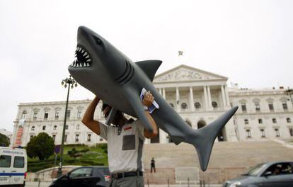 Un hombre carga a un tibur&oacute;n durante una protesta en Lisboa.